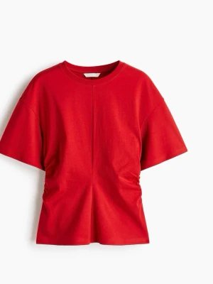 Röd t-shirt med snörningsdetalj - Cool röd t-shirt i bomull med korta ärmar och rund hals. T-shirten har en unik snörningsdetalj i midjan som ger en snygg twist till den klassiska modellen. Perfekt för dig som vill ha något enkelt men ändå speciellt.