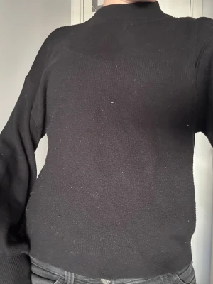 Svart stickad tröja med hög hals - En svart stickad tröja med hög hals och långa ärmar. Tröjan har en rak passform och är väldigt bekväm. Endast använd ett fåtal gånger. Storlek xs