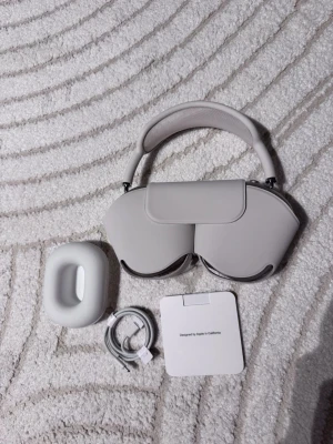 Apple AirPods Max silver over-ear - Snygga Apple AirPods Max i silver med mjuka öronkuddar i mesh och justerbart huvudband. Over-ear design i aluminium och rostfritt stål. Kommer med smart case, laddkabel och dokumentation. Perfekta för musik, gaming eller film.