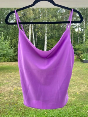 Lila linnetopp i satin med draperad urringning, stl S - Ett lila linne i satin från Gina Tricot. Linnet är i storlek 36 men passar bra till 34 också 💜 Endast använt en gång 🌷 Justerbara axelband.  Längd: 44 cm
