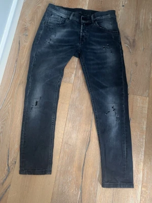 Svarta slimjeans med slitningar - Säljer ett par svarta skinny jeans med coola slitningar och tvättade detaljer. Jeansen har fem fickor och smal passform som sitter snyggt. Perfekta för dig som gillar en trendig och avslappnad stil.