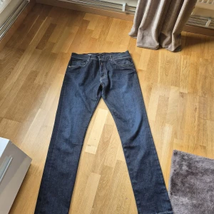 Mörkblå raka jeans herr - Säljer ett par mörkblå jeans med rak passform och klassisk femficksdesign. Jeansen har normal midja och stängs med dragkedja och knapp. Materialet är kraftig denim i bomull. Perfekta till en avslappnad stil.