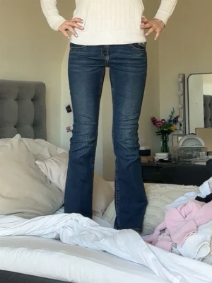 Mörkblå bootcut jeans - Säljer ett par mörkblå bootcut jeans med klassiska kontrastsömmar och snygga fickdetaljer bak. Jeansen har låg midja och är tillverkade i stretchigt denim för skön passform. Perfekta till sneakers eller boots.