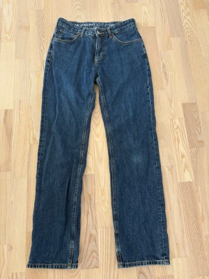 Mörkblå low straight jeans - Säljer ett par klassiska mörkblå jeans med rak passform och fem fickor. Jeansen har normal midja och tydliga kontrastsömmar. Tillverkade i slitstark denim, perfekta för en avslappnad och tidlös stil. W: 28 och L: 32 (skulle säga att de passar för någon som har S/36)