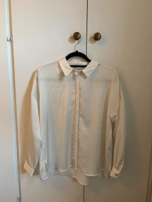 Vit skjorta - Klassisk vit skjorta från Zara. Skjortan har lång ärm, dolda knappar framtill och en mjuk, lätt struktur i tyget. Perfekt till jeans eller kjol för en clean och enkel look.