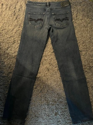 Mörkblå raka jeans från Diesel - Säljer ett par mörkblå raka jeans från Diesel med snygga slitningar och klassisk femficksmodell. Jeansen har broderade detaljer på bakfickorna och metallknapp framtill. Materialet är mjukt denim som sitter skönt hela dagen.