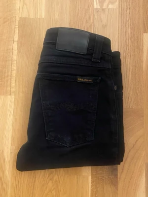 Svarta nudie jeans  - Säljer dessa svarta nudie jeans i modell -skinny sam, 9/10 skick, pytte lite tecken på användning se på bilderna, storlek 27/32. Passar dig bäst som gillar jeansen lite mer tajta eller om du tillexempel har lite smalare ben. Säg bara till om det är nått, mvh Filip 