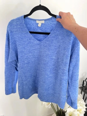 Blå stickad tröja från H&M, stl S - En blå stickad tröja från H&M som är sparsamt använd 💙 Tröjan är superstretchig och har en fin v-ringning. Storlek XS och passar bra till mig som har S. Längd: 60cm - Axel: 50cm - Byst: 104cm
