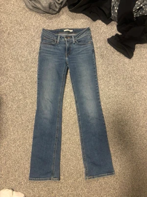 Blå bootcut jeans med fem fickor - Ett par klassiska blå bootcut jeans i denim med låg midja och fem fickor. Jeansen har en lätt tvättad look och raka ben som smalnar av upptill och blir vidare nedtill. 