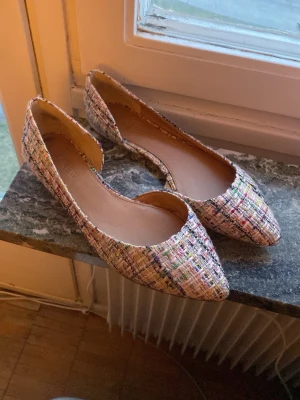 Flerfärgade ballerinaskor från J.Crew - Säljer ett par ballerinaskor från J.Crew med spetsig tå och flerfärgat rutigt tyg. Skorna har en elegant och modern look med öppen sida och mjuk innersula. Perfekta för dig som vill ha något unikt och färgglatt till din outfit.
