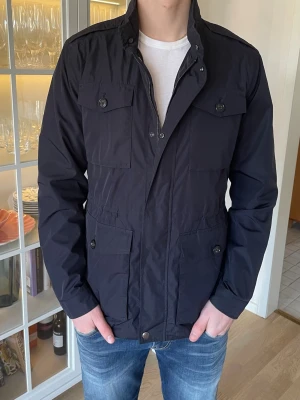 Mörkblå Fieldjacka från Massimo Dutti - S - Jag säljer den här riktigt feta fieldjackan från Massimo Dutti. Den är i väldigt fint skick utan defekter. Nypris låg på ca 2499kr och jag säljer den för 799kr. Tveka inte att höra av er!