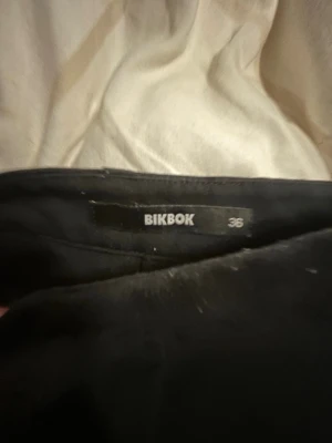 Svarta kostymbyxor från BikBok - Säljer ett par svarta kostymbyxor från BikBok i storlek 36. Byxorna har raka ben och hög midja, vilket ger en clean och stilren look. Perfekta att matcha med en crop top eller oversized skjorta för en trendig vibe.