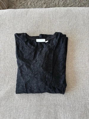 Svart spetsblus med kort ärm - Snygg svart blus i spets med rund halsringning och korta ärmar. Den är i strl L men är lite lite stor för mig som brukar ha S/XS