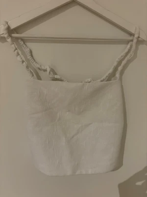 Vit linnetopp från Zara -  vit linnetopp med twistade axelband och öppen rygg. Toppen har en rak, croppad passform! Sällan använd. Storlek L, känns som S/M