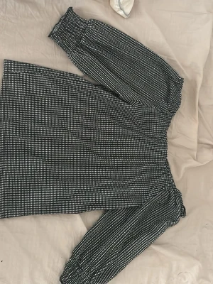 Svartvit offshoulder-blus med rutmönster - Trendig svartvit offshoulder-blus med små rutmönster. Blusen har resår vid axlar och ärmslut för en snygg passform. 