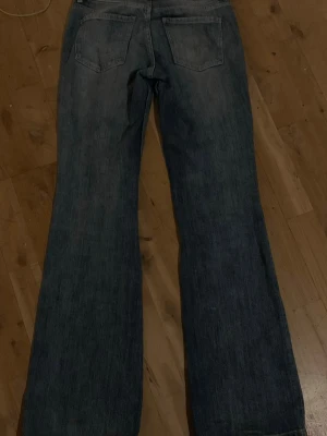 Blå bootcut jeans från Bershka - Säljer ett par blå bootcut jeans från Bershka i klassisk denim. Jeansen har normal passform upptill och vida ben från knät och ner. Perfekta för dig som gillar retrovibbar och vill ha ett par jeans som sticker ut lite extra.