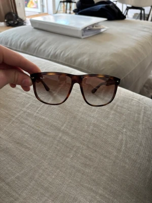 Bruna Ray-Ban solglasögon wayfarer - Snygga solglasögon från Ray-Ban i klassisk wayfarer-modell med brunmelerad båge och bruna tonade glas. Perfekta för soliga dagar och ger en cool vibe till din outfit.