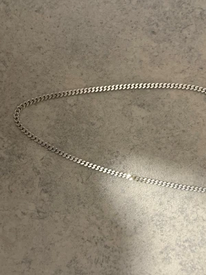 Silverhalsband 925 kedja - Snyggt halsband i äkta silver (925) från VHA. Kedjan har en klassisk, platt design som ger en stilren look. Perfekt för dig som gillar minimalistiska smycken i silverfärg.