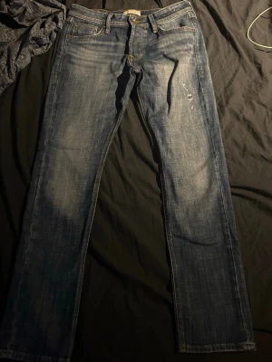 Blå  jeans  - Säljer ett par klassiska blå jeans raka ben och snygga slitningar. Slimm 