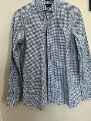 Blårutig skjorta från Massimo Dutti - Superbra skick. Är storlek M men skulle säga mer S/M.  Klassisk blårutig skjorta från Massimo Dutti i slim fit-modell. Skjortan har långa ärmar, knappar framtill och är tillverkad i mjuk bomull. Perfekt för en clean och stilren look.