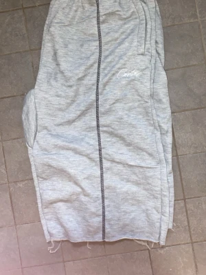 Grå sweatshorts från Corteiz - Ljusgrå sweatshorts från Corteiz med elastisk midja och synliga svarta sömmar framtill. Shortsen har råa kanter nedtill och sidofickor. Perfekta för chill eller träning.