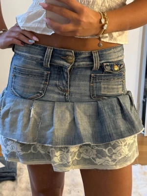 Jeanskjol med spetsvolang från Only - Supersöt kort jeanskjol från Only med volangkant och vit spetsdetalj längst ner som jag gjort om från ett par jeans. Kjolen har klassiska jeansfickor, bälteshällor och knäppning fram. 