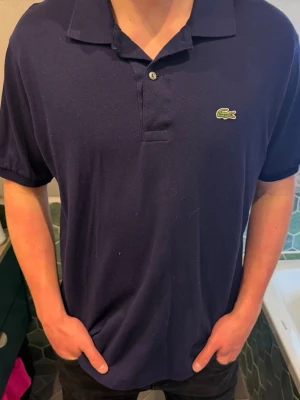 Mörkblå pikétröja från Lacoste - Snygg piké från Lacoste nyskick. Skulle uppskatta att den är i M/L! 