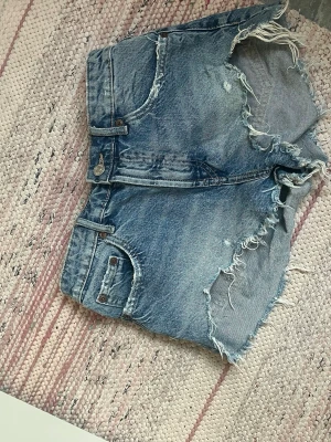 Blå denimshorts med slitna detaljer - Säljer detta par jeansshorts efter som jag köpte de här på plick men det var för små så säljer dem.  (De är små i storleken)