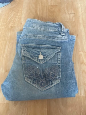 Blå bootcut jeans med broderad ficka - Säljer ett par ljusblå bootcut jeans från Gina tricot . De är i mycket bra Skick . De har snygga detaljer på på fickorna där bak 