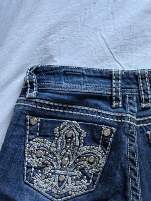 LA Idol shorts med broderad ficka - PRIS KAN DISKUTERAS! Säljer ett par blå shorts från LA Idol USA med unika bakfickor dekorerade med vit brodyr och silvriga nitar i ett snyggt mönster. Jeansen har kontrastsömmar och detaljer som verkligen sticker ut. Perfekta för dig som gillar statement-plagg! Skriv för mått! Köpta i Amsterdam second hand, men säljer då dem knappt används och inte är min stil. Ordinarie pris: 1200kr 