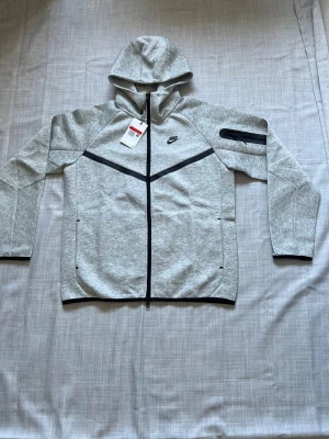 Nike tech fleece hoodie grå L - helt ny  - Helt ny Nike Tech Fleece hoodie i grå säljes. Väldigt efterfrågad modell och perfekt till vardag eller streetwear outfits. Sjukt clean fit och väldigt bekväm. Oanvänd och i nyskick storlek L. Snabb frakt och paketpris finns 
