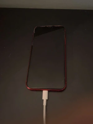 Röd iPhone 11 från Apple - Säljer en snygg röd iPhone 11 från Apple. Telefonen har en stilren design med glasbaksida och aluminiumram. Baksidan har två kameror och Apple-loggan i silver. Perfekt för dig som vill ha en färgstark och modern mobil. Batteri 80%