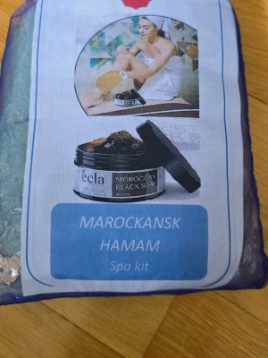 Marockansk Hamam Spa Kit - Lyxigt marockanskt hamam spa kit med Moroccan Black Soap, skrubbvante och tvättpåse. Perfekt för en djuprengörande och återfuktande hudvårdsrutin hemma. Kommer i en blå genomskinlig förvaringspåse.