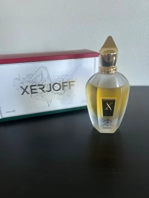 Xerjoff Naxos Eau de Parfum 100ml - Lyxig parfym från Xerjoff, modellen Naxos. Flaskan är elegant med frostat glas och gulddetaljer, samt en unik guldfärgad kork. Doften kommer i en exklusiv förpackning med konstnärlig design. Perfekt för dig som gillar exklusiva och sofistikerade dofter. Endast 80/100 Ml
