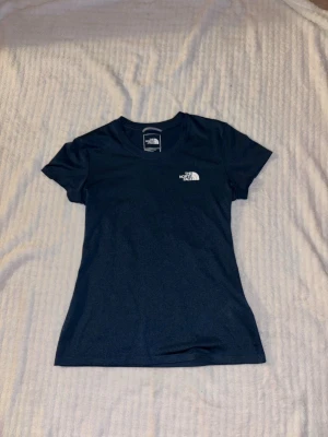 Mörkblå t-shirt från The North Face - Snygg mörkblå tränings t-shirt från The North Face med vit logga på bröstet. Klassisk rund halsringning och korta ärmar. 