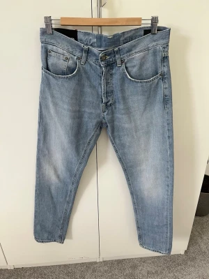 Ljusblå raka jeans från DonDup  - Säljer ett par ljusblå jeans från DonDup med raka ben och klassisk femficksdesign. Jeansen har subtila slitningar för en avslappnad look. Tillverkade i bomullsdenim.