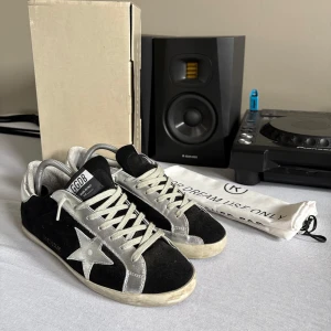 Golden Goose svarta och silver sneakers - Golden Goose sneakers i svart mocka med silverfärgade detaljer. Perfekta för dig som gillar en unik och trendig look.   Storlek: 43 men passar både 42 och 44. Lite slitna i hälen men fortfarande grymt skick.