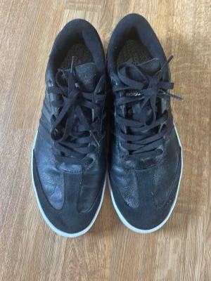 Adidas Golfskor Läder - Snygga svarta golfskor från Adidas. Skorna är låga och har ovandel i läder med detaljer i mocka, samt vita sulor och svarta skosnören. Perfekta för en stilren och sportig look. Storlek 43 men står UK 9. Dom sitter mindre vad jag känner så om du har 41 eller 42 borde de passa bättre. Kan sänka pris till max 250 vid snabb affär!