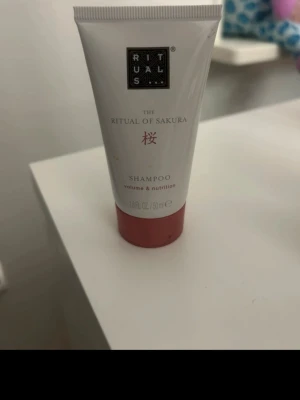 Rituals The Ritual of Sakura schampo - Rituals The Ritual of Sakura schampo i en vit och rosa tub på 50 ml. Ger volym och näring till håret. Tuben har en stilren design med svarta och rosa detaljer och är perfekt att ta med på resan.