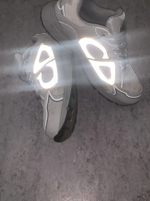 Gråa sneakers från CD - Snygga grå sneakers från CD medreflekterande detaljer och meshpaneler. Skorna har en chunky sula och lågt skaft för en modern look. Perfekta för dig som gillar streetwear och vill sticka ut med coola detaljer.