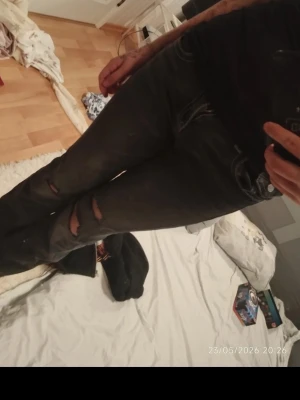 Svarta slitna bootcut jeans - Säljer ett par svarta bootcut jeans med slitningar och hål vid knäna. Jeansen har klassisk femficksdesign och låg midja. Perfekta för en edgy och avslappnad stil.