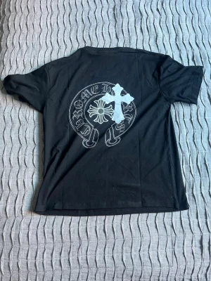 Svart Chrome Hearts t-shirt - Säljer en svart t-shirt från Chrome Hearts med stort vitt tryck på ryggen och mindre tryck på bröstet. 