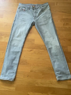 Ljusblå raka jeans från Diesel - Säljer ett par ljusblå jeans från Diesel med raka ben och klassisk femficksdesign. Jeansen har diskreta slitningar och röda detaljer på bakfickan. Perfekta för en avslappnad och trendig look.