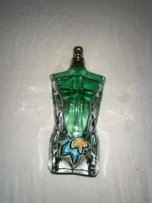 Jean Paul Gaultier paradise garden parfym - Unik parfymflaska från Jean Paul Gaultier formad som en manlig torso i grönt glas med broderad detalj framtill. Flaskan har metallfärgad spraytopp och en cool, modern design som sticker ut i badrumshyllan. Runt 75-80% kvar i flaskan