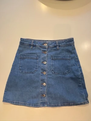 Blå jeanskjol med knappar - Säljer en blå jeans kjol från Gina. Säljer då den är för liten för mig och inte används💙