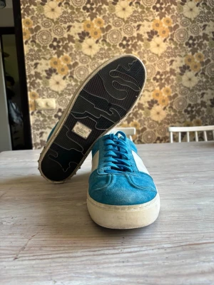 valentino flycrew - Snygga blåa sneakers från valentino med vit sula och vit sidopanel. Ovandelen är i mocka och textil, med klassisk snörning och låg profil. Sulan har ett unikt mönster undertill. Perfekta för dig som gillar retrostil och färg. Hör av om du har några frågor. Pris kan diskuteras 