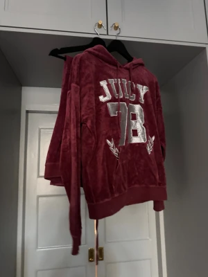 JUICY COUTURE mysset (hoodie&byxor) - Mysig vinröd hoodie och mjukisbyxor velourmaterial från Juicy Couture med tryck '78' i silver och vita detaljer framtill. Tröjan har huva och ribbade muddar vid ärmslut och nederkant. Byxorna är utsvängda & lågmidjade. HOODIE: S BYXOR: XS