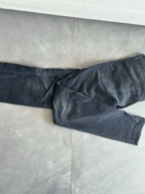 Svarta Replay jeans Anbass herr - Säljer ett par svarta jeans från Replay, modell Anbass. Jeansen har klassisk femficksdesign, smal passform och är tillverkade i stretchigt material för extra komfort. Perfekta för dig som gillar en stilren och modern look.