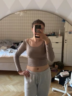 Beige croppad långärmad topp - Snygg croppad topp i beige med lång ärm och rund halsringning. Perfekt att styla med höga jeans eller kjol för en trendig look. Mjuk och stretchig känsla, passar dig som gillar en enkel men stilren vibe.