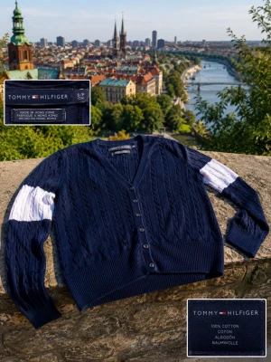 Svart kofta från Tommy Hilfiger - Svart kabelstickad kofta från Tommy Hilfiger med v-ringning och knappar framtill. Ärmarna har en bred ljusblå och vit rand som ger en cool kontrast. Perfekt för lager-på-lager och snygg till jeans eller kjol. Fråga gärna om de är något du undrar!